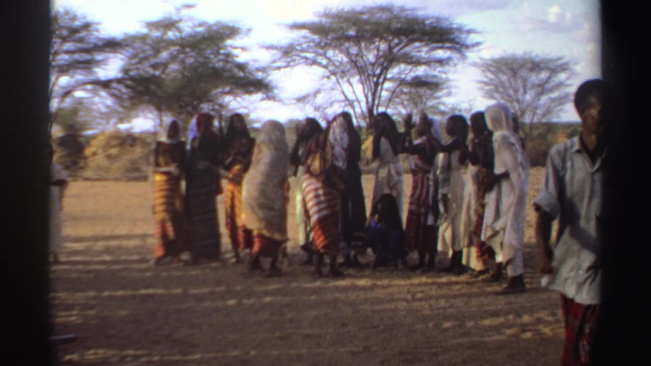 A group of women gathers outdoors while a person stands near the right edge.
