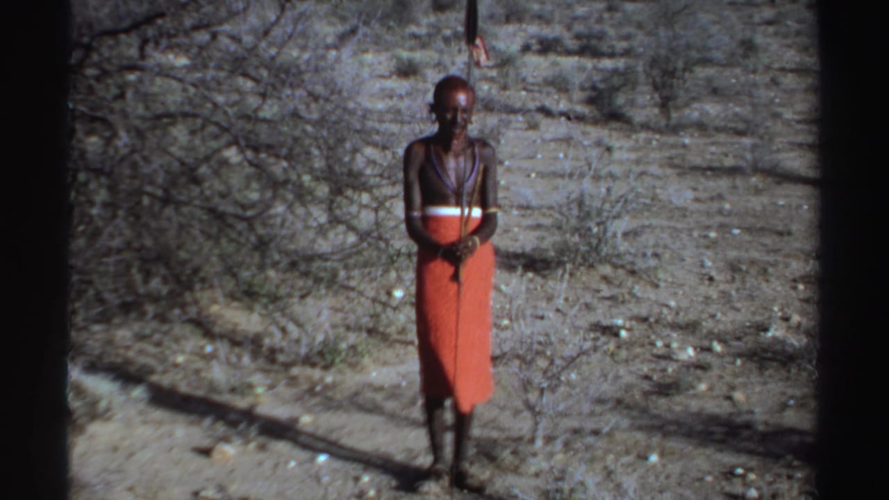 Man standing front-facing in a dry scrub landscape with spear upright.