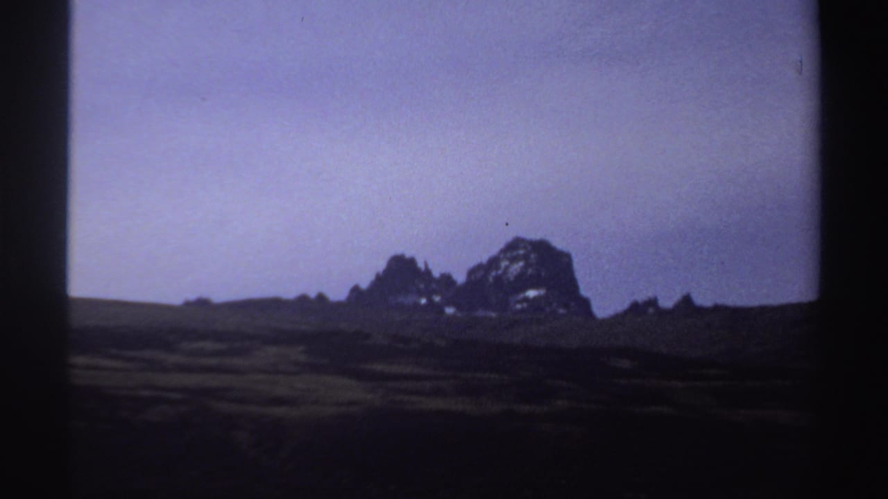 Dark rocky mountain ridge beneath a purple-blue twilight sky.