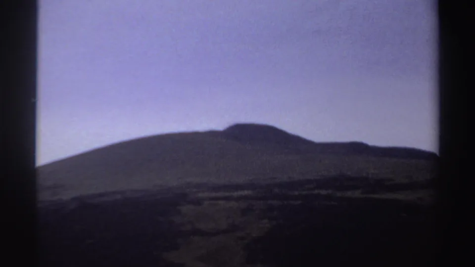 1969 Sudan 8mm frame showing a dark hillside silhouette with faint layered terrain below a purple sky.
