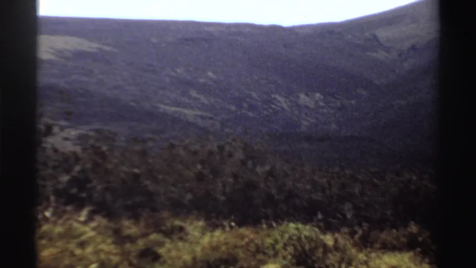 1969 Sudan 8mm view of brush, grassy foreground, and a distant mountain ridge under a clear bright sky.
