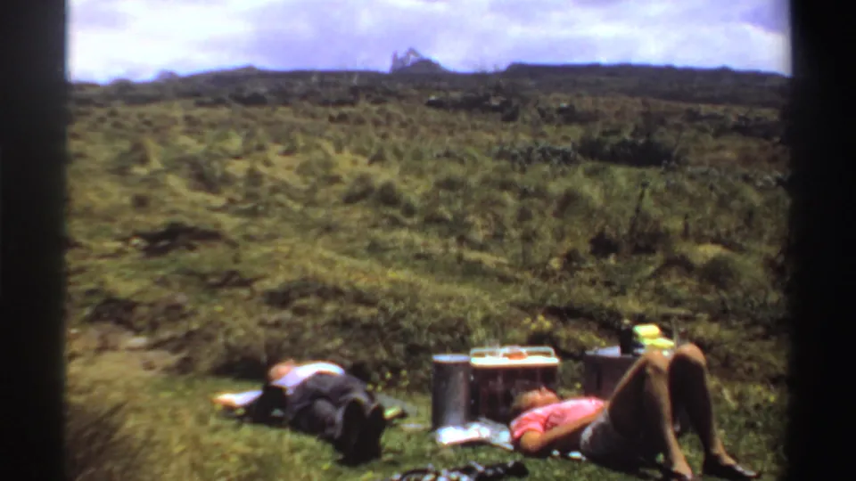 Two people remain reclined beside camping supplies on a grassy hillside, with Sudan location and 1969 date supported by metadata.