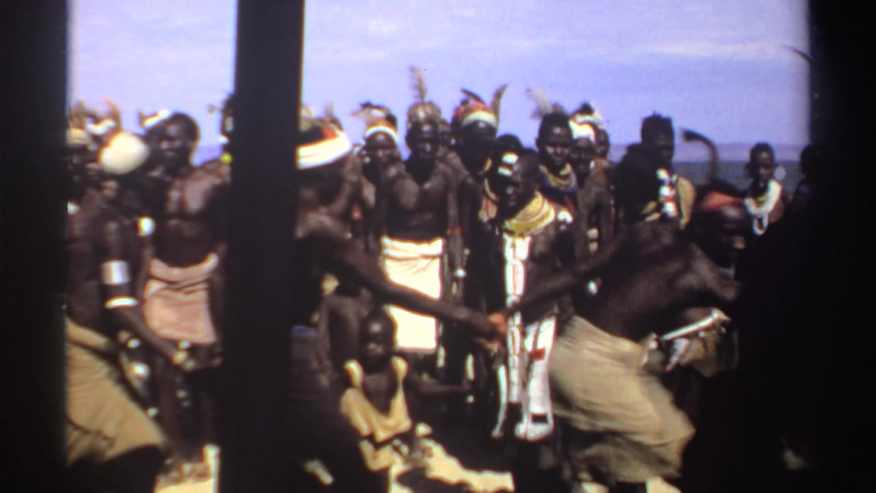 Group of men in traditional attire dancing outdoors near the camera.