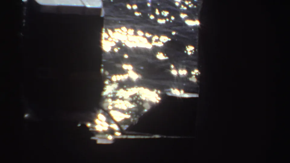The final 8mm frame looks past dark pier posts toward bright, rippling water in the Sudan fishing scene.