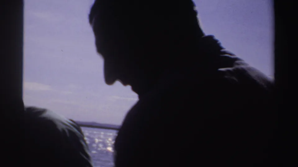 A silhouetted adult looks across open water in the 1969 Sudan sea-fishing home movie.