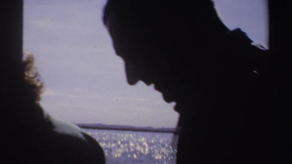 1969 Sudan 8mm frame with a silhouetted adult man leaning forward on a boat against a bright sea horizon.