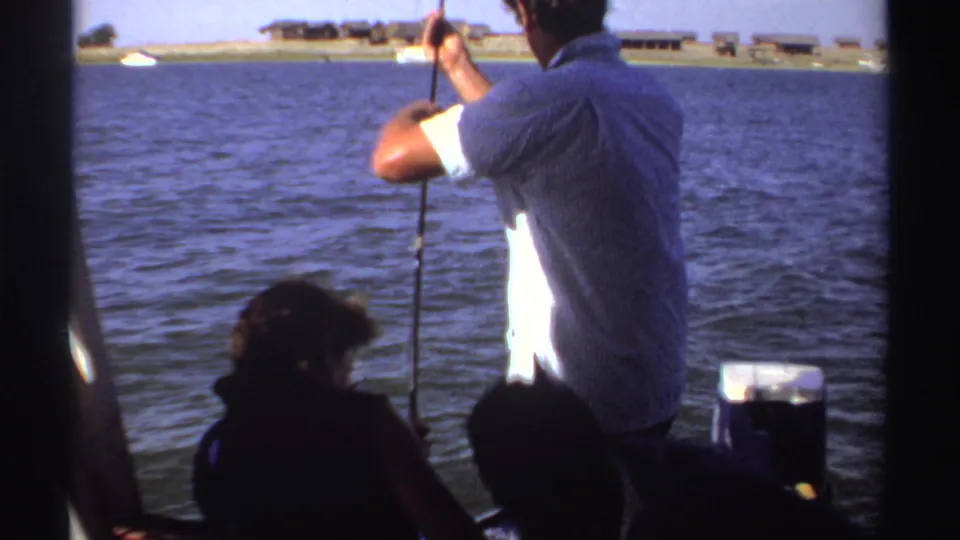 A 1969 Sudan boat scene shows the man leaning into the fishing line while another person sits silhouetted near the camera.