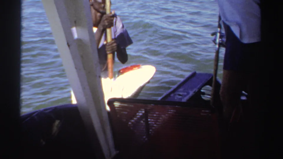 1969 Sudan 8mm frame showing a large fish being brought toward a small boat, with men and fishing gear visible nearby.