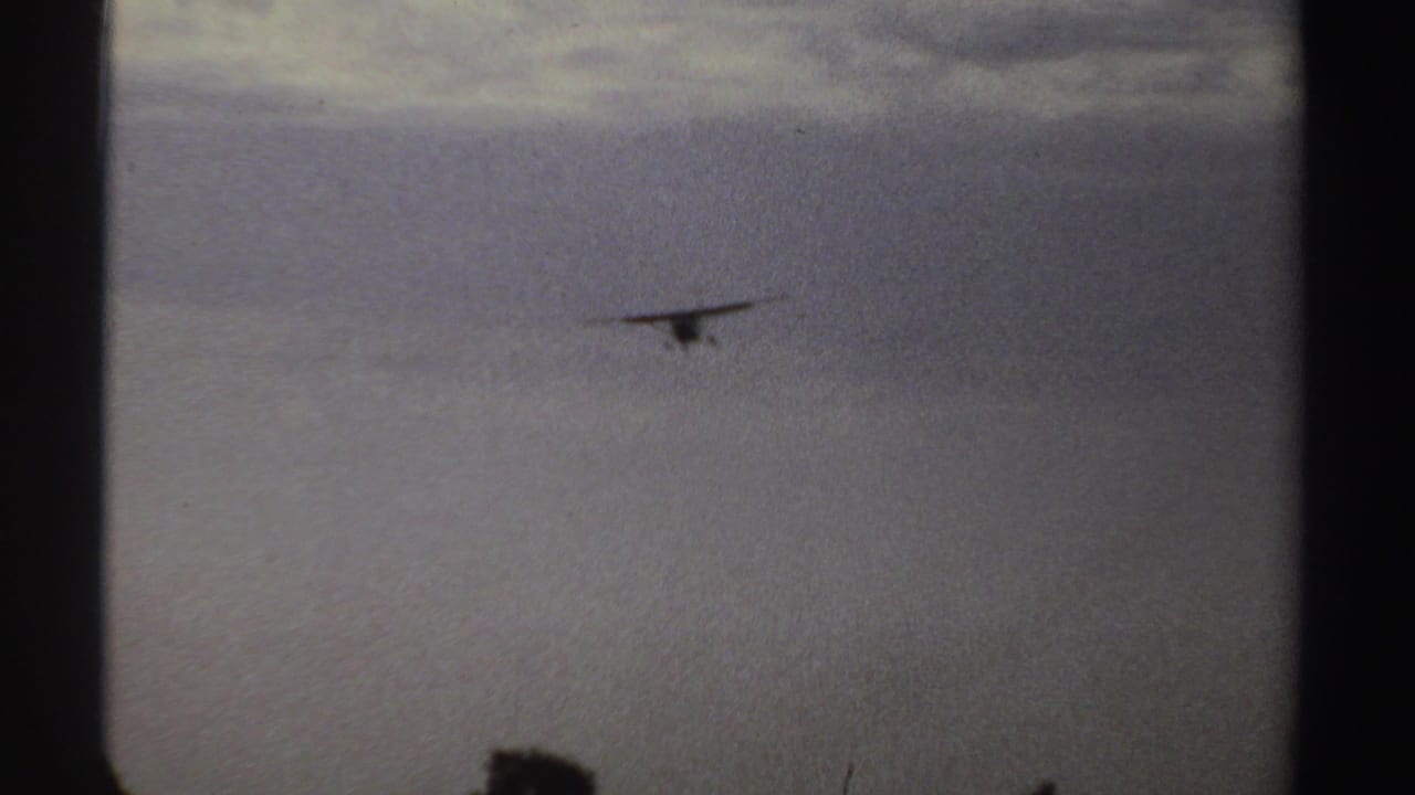 Small plane far off against a cloudy sky above a flat horizon.