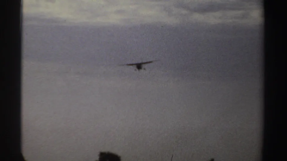 Distant small propeller plane approaches over an open Sudan landscape in 1969 home-movie footage.