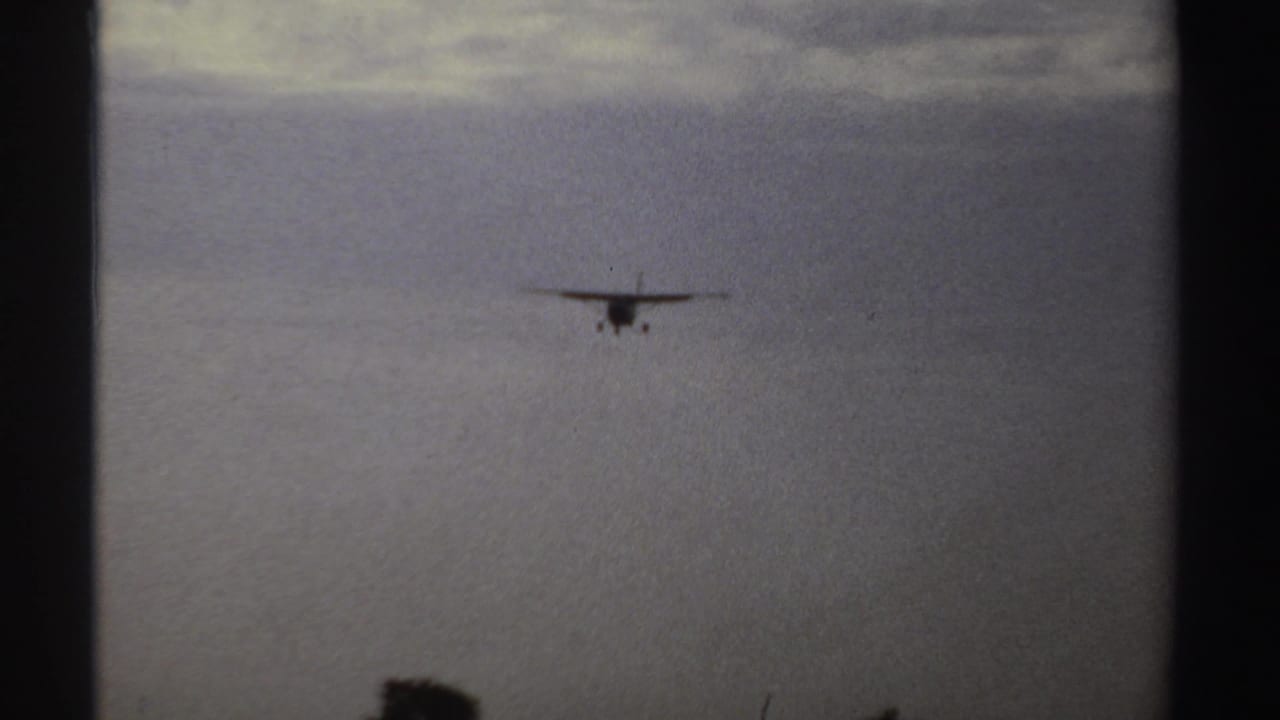 Small propeller aircraft remains distant but clearer against the overcast sky in the Sudan 1969 footage.