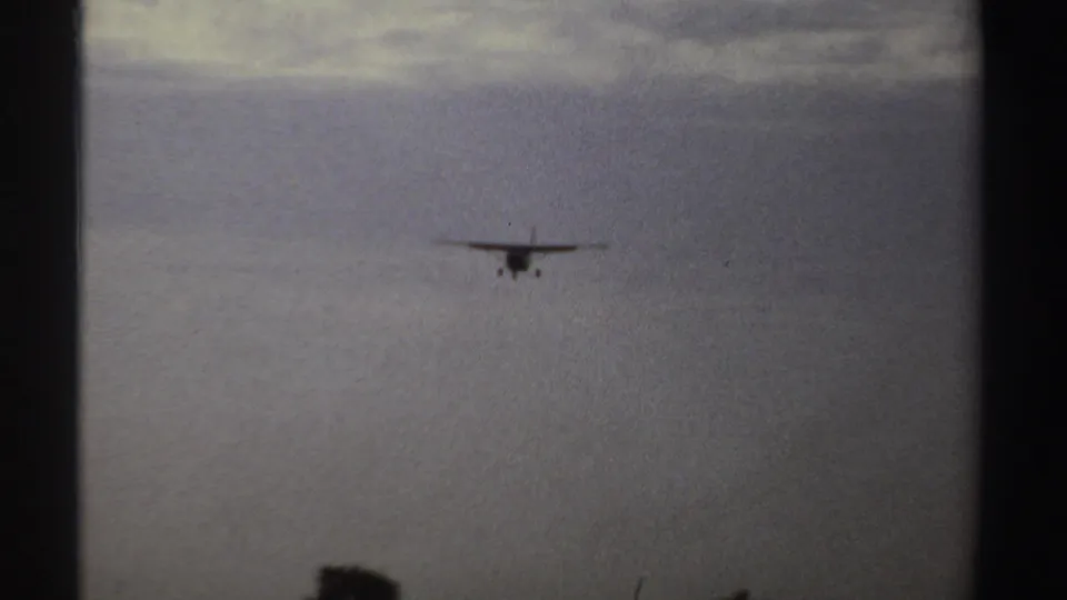 Small propeller aircraft remains distant but clearer against the overcast sky in the Sudan 1969 footage.