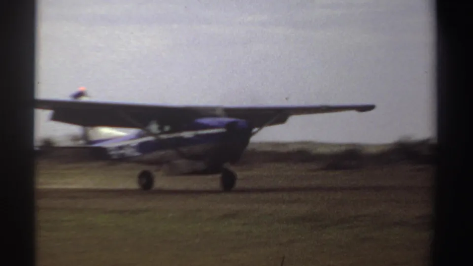 The small aircraft rolls across the open field after landing, with its propeller area blurred by motion.
