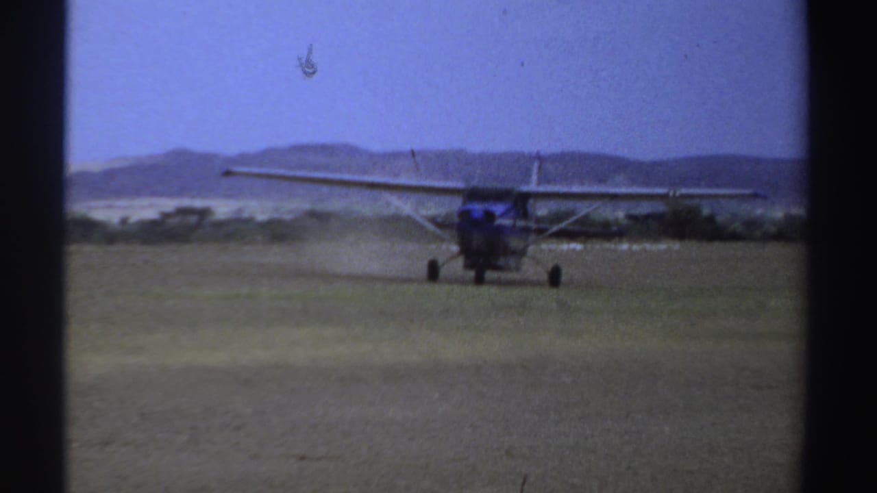 Propeller aircraft continues across the grass field with dust visible behind the wheels.