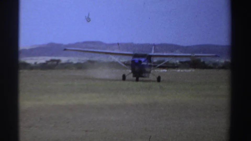 The aircraft advances along the Sudan grass strip, framed by 8mm gate borders and a low hill line in the background.