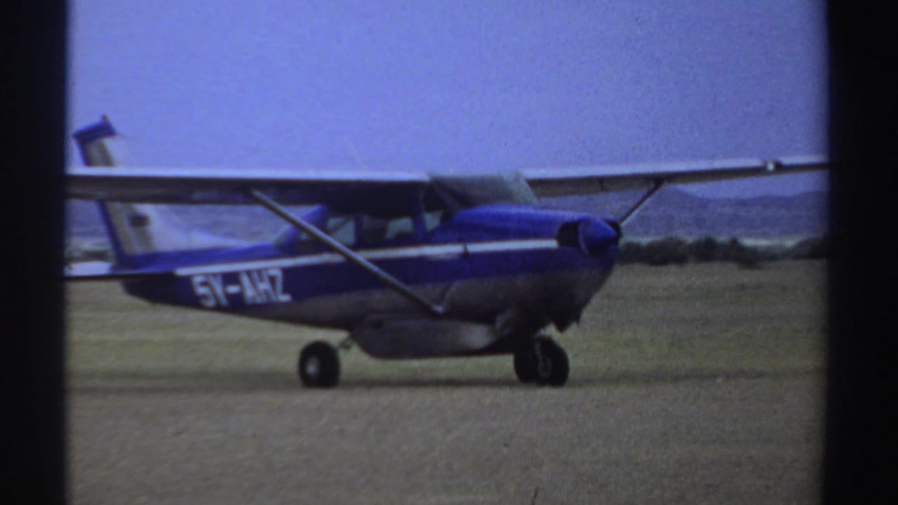 The blue and silver plane, with visible registration markings, taxis broadside across the Sudan airfield in 1969 home-movie footage.
