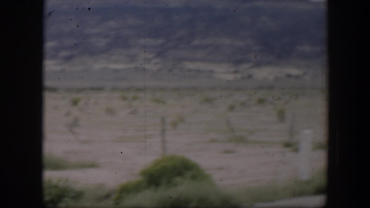 1951 Utah home-movie frame with a soft, moving view of scrubby desert land and low mountains under a muted sky.