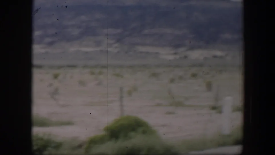 1951 Utah home-movie frame with a soft, moving view of scrubby desert land and low mountains under a muted sky.