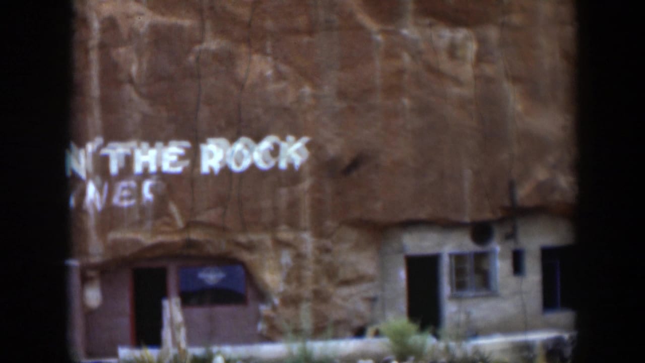 1951 Utah 8mm frame showing part of the Hole N' The Rock Diner sign on a sandstone cliff facade with an entrance below.
