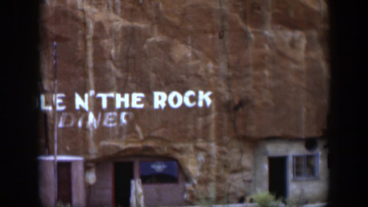 1951 Utah home-movie frame with the Hole N' The Rock Diner sign visible on a sandstone cliff, above the exterior entrance.