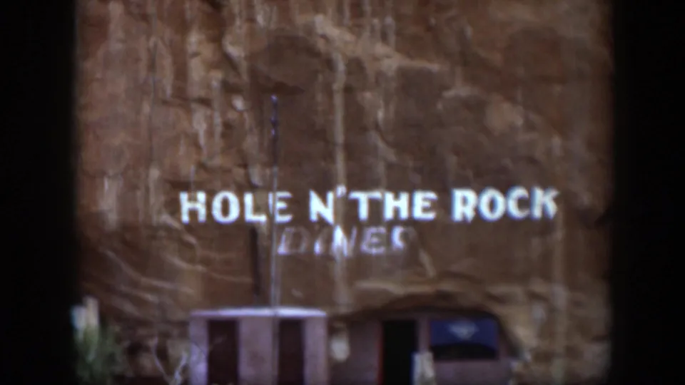 1951 Utah 8mm frame showing the Hole N' The Rock Diner sign centered on a textured sandstone wall above the entrance.