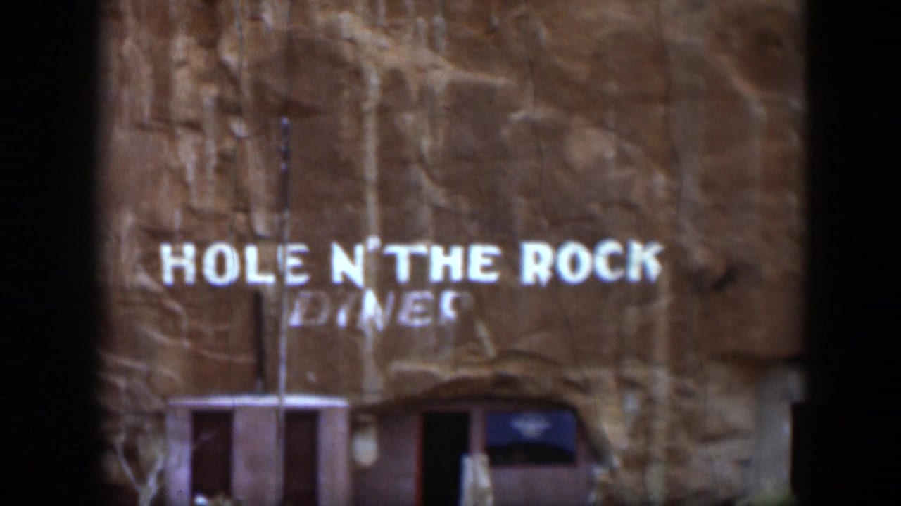 1951 Utah home-movie frame showing the Hole N' The Rock Diner sign painted on a sandstone cliff face.