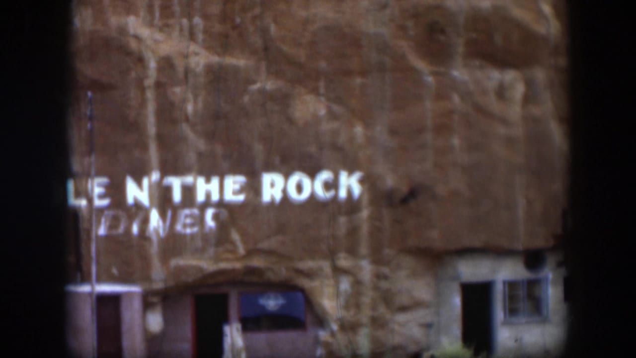 Partial Hole N' The Rock Diner sign on sandstone with an entrance and small window below.