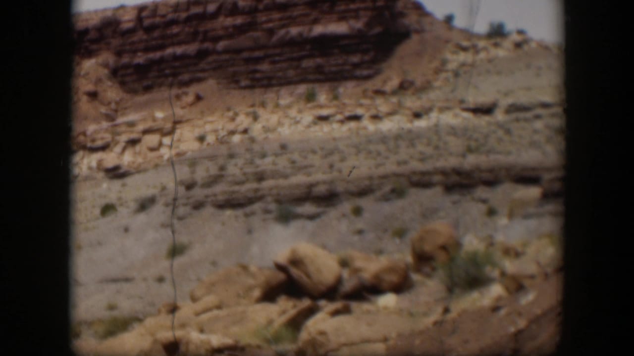 1951 Utah 8mm frame showing stratified desert rock, loose boulders, dry ground, and visible film wear.