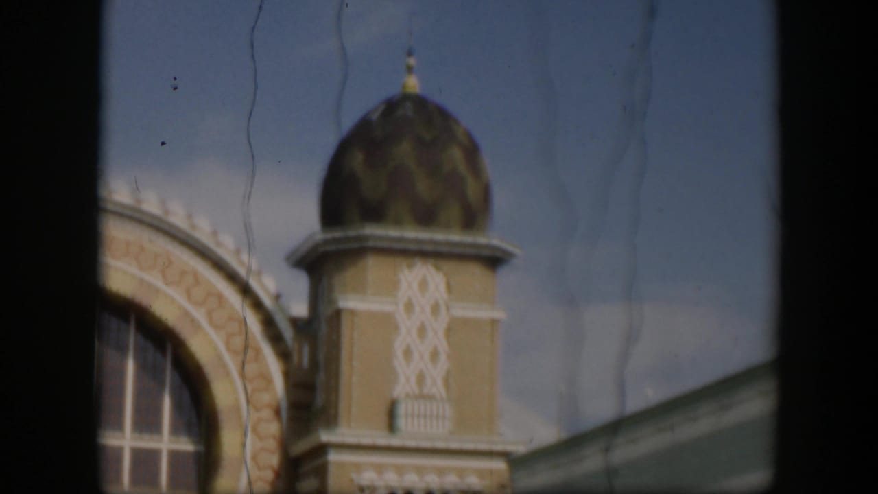 Ornate zoo building facade with patterned dome, arch, window, and film frame borders.