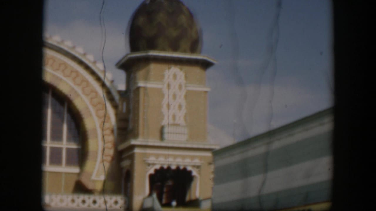 1951 Utah home-movie frame of a domed zoo building tower with decorative trim, arched window area, awning edge, and soft film grain.