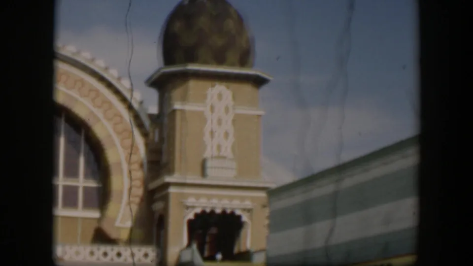1951 Utah home-movie frame of a domed zoo building tower with decorative trim, arched window area, awning edge, and soft film grain.