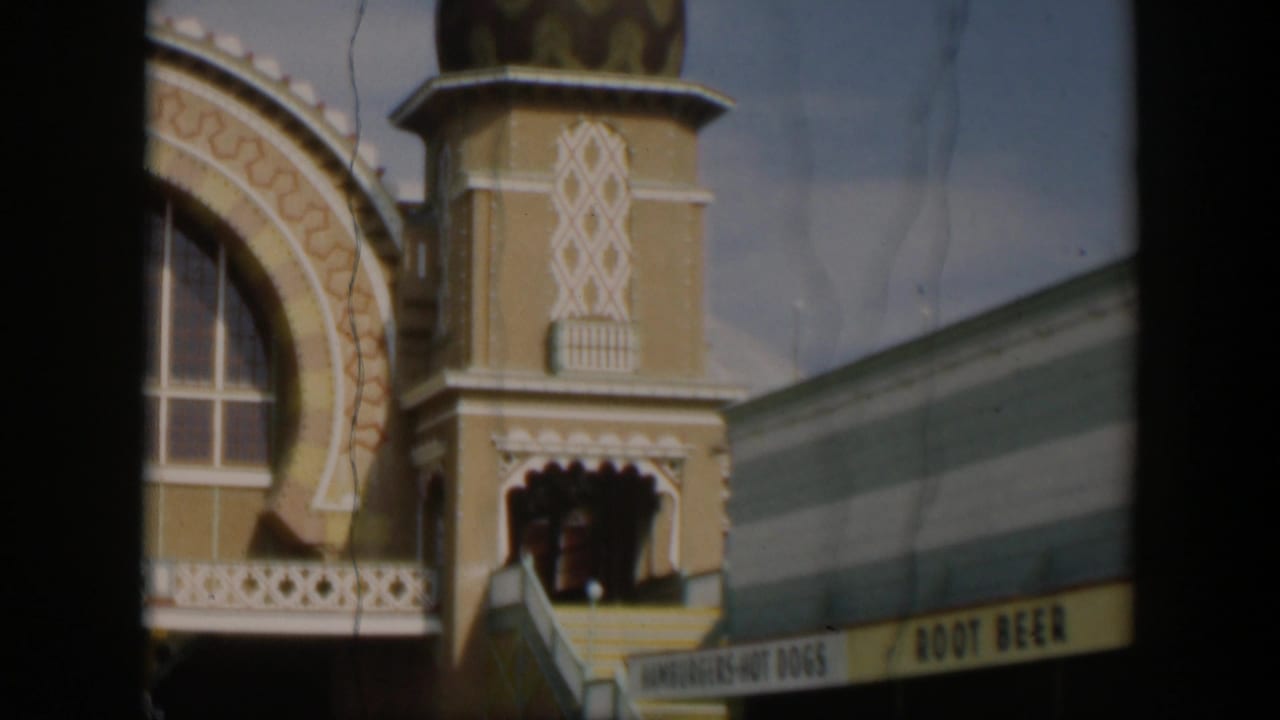 1951 Utah 8mm frame showing the domed zoo building, ornate facade, striped awning, and a partially visible refreshment sign below.
