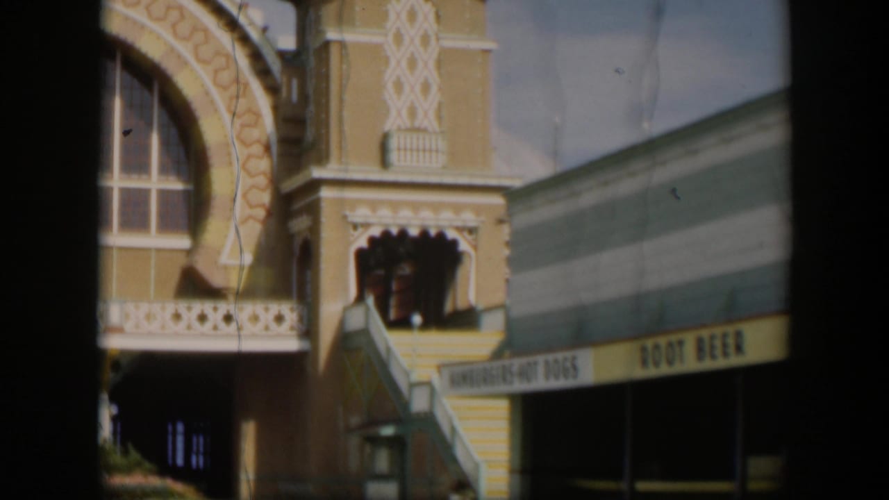1951 Utah 8mm frame with the ornate domed zoo building, striped awning, visible root beer sign, and small visitor figures near the entrance.