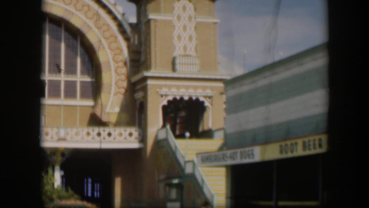 1951 Utah 8mm frame showing part of an ornate facade with arched window trim, domed tower detail, balcony rail, and food-stand signage.