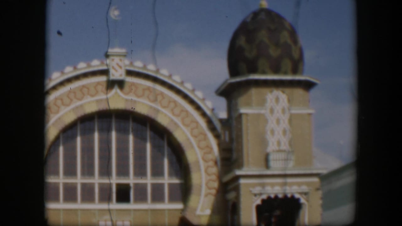 1951 Utah 8mm frame centered on an ornate yellow-and-cream facade with a large arched window, patterned trim, and domed tower.