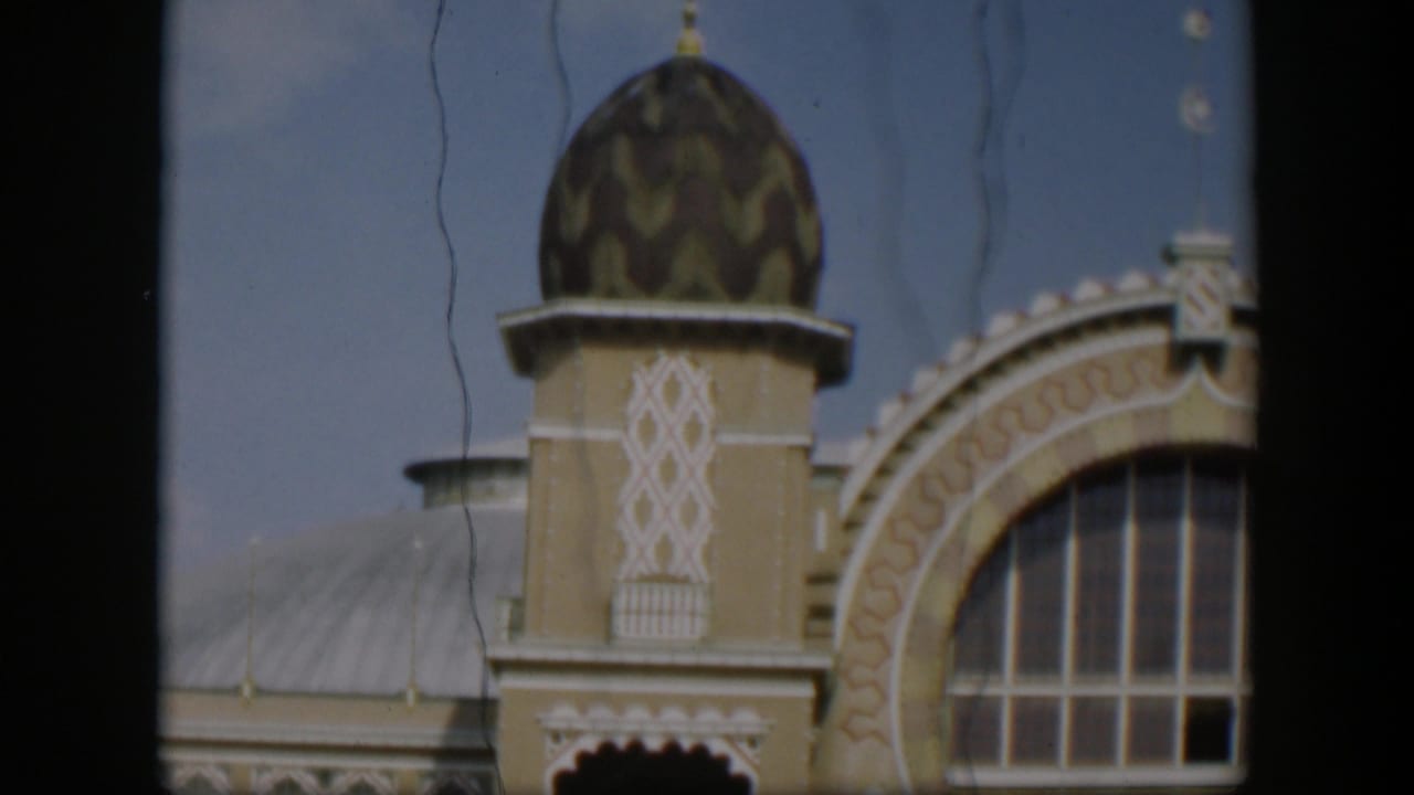 1951 Utah 8mm frame looking upward at an ornate religious building with a domed tower, patterned trim, roofline, and partial arched window.