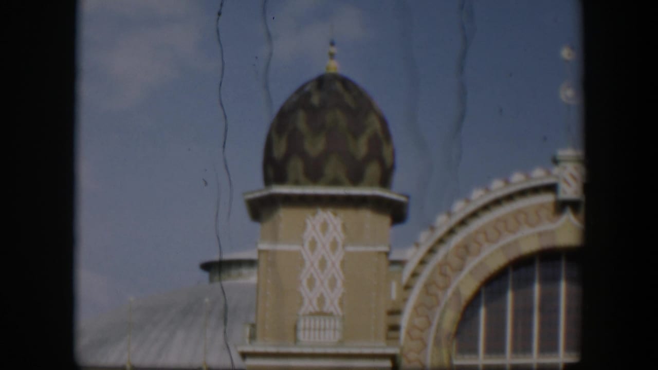 1951 Utah 8mm frame showing the upper facade of an ornate domed building with a large arched window, viewed through dark foreground bars.
