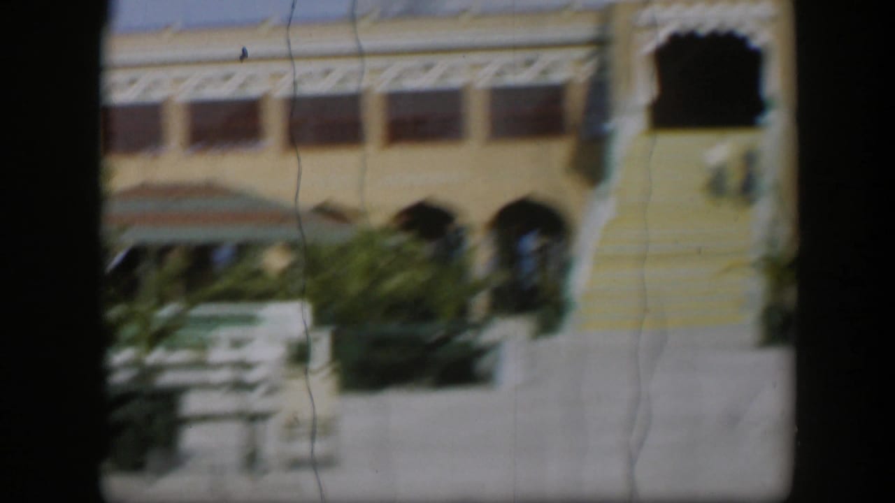 Soft 8mm view of a resort facade with striped stairs, arches, benches and plants.