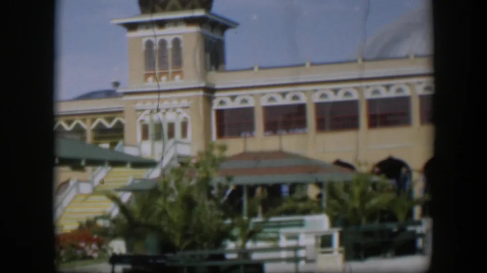 1951 Utah-labeled 8mm frame showing a beige building with a decorative tower, chevron-patterned dome, striped steps, and palms in front.