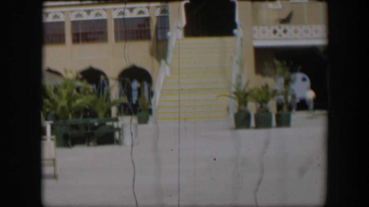 1951 Utah 8mm frame showing the Salt Lake Tabernacle entrance area with striped steps, potted palms, benches, and small visitors nearby.