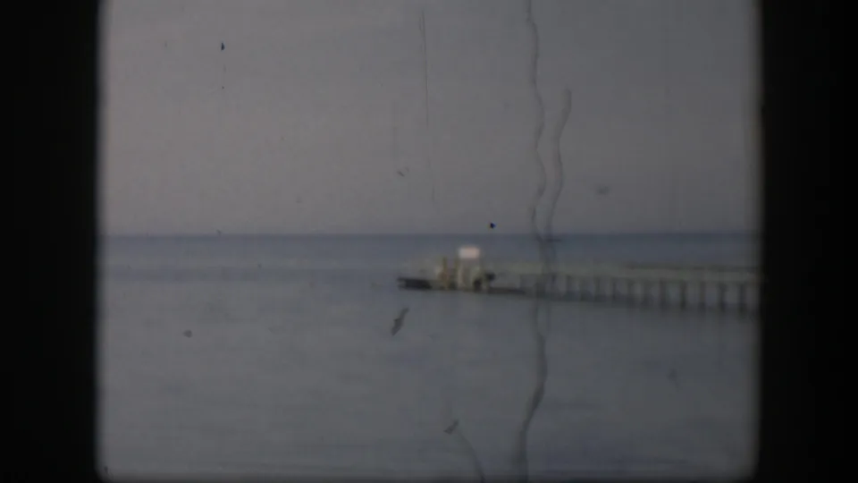 Soft 8mm view of a long pier and small pale structure on a Utah waterfront in 1951, framed by visible scan borders.