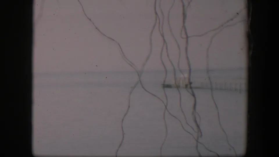 1951 Utah 8mm frame with loose foreground strings over a soft gray-white horizon and a small distant pier-like form.