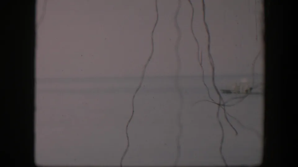 1951 Utah 8mm view of delicate strings against a faded gray background, with a small distant structure near the horizon.