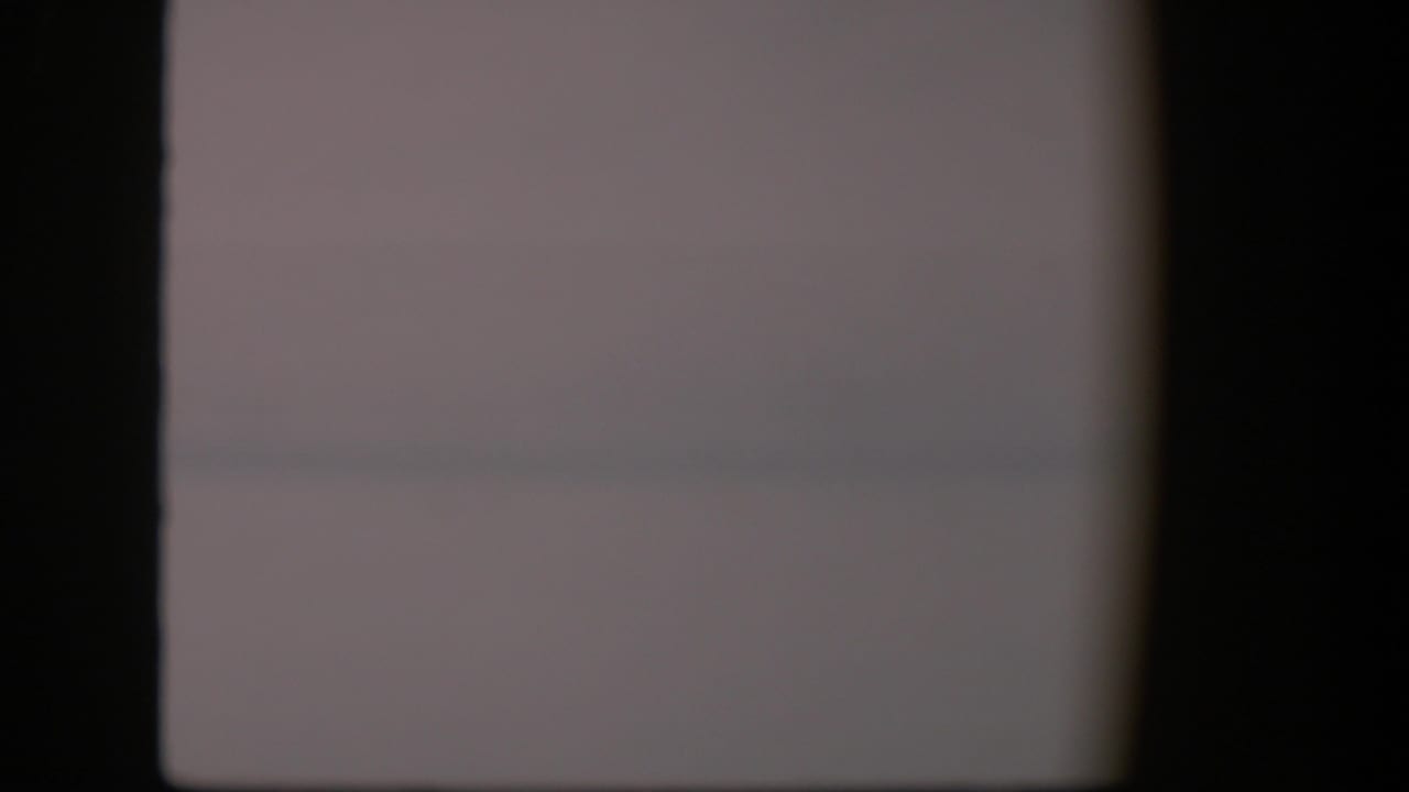 Pale low-contrast sky or waterline with dark film gate edges.
