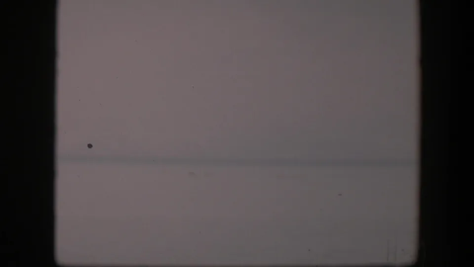 1951 Utah home-movie frame showing a faint distant line, pale sky, dust specks, and a dark film-edge bar.