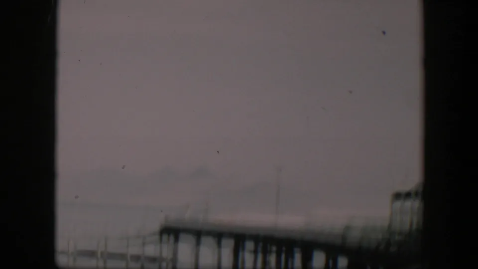 1951 Utah 8mm frame with a dim possible shoreline, dark gate borders, soft exposure, dust, and indistinct foreground detail.