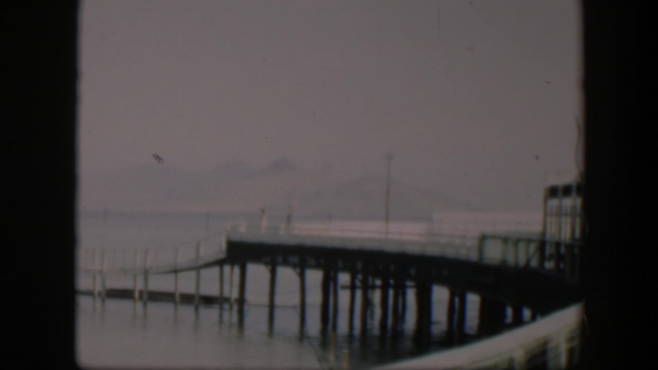 1951 Utah 8mm frame showing a fog-softened pier over still water, with distant hills barely visible.