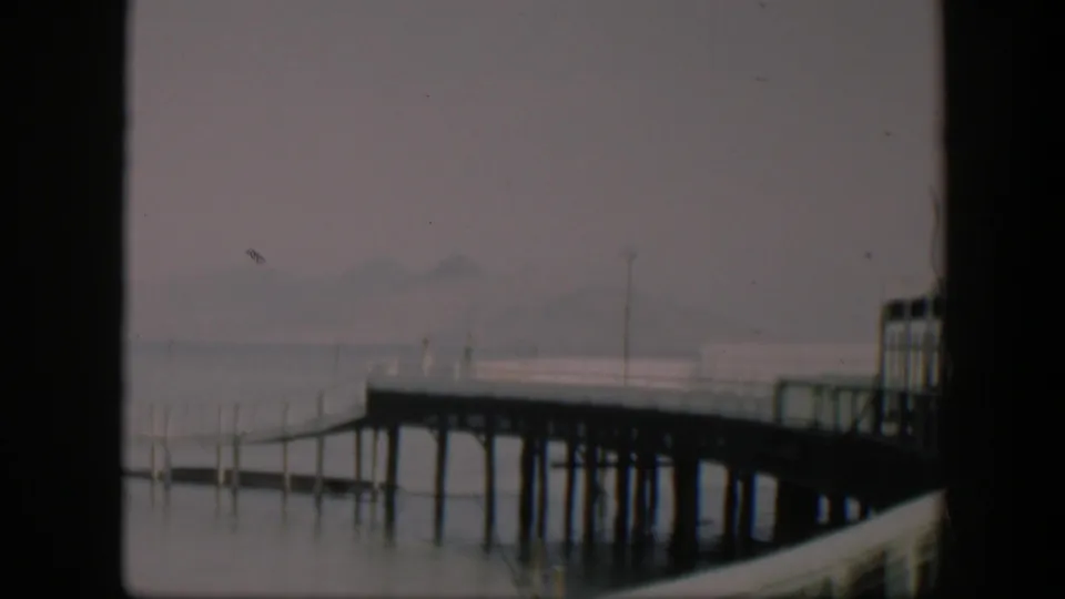 1951 Utah 8mm frame showing a fog-softened pier over still water, with distant hills barely visible.