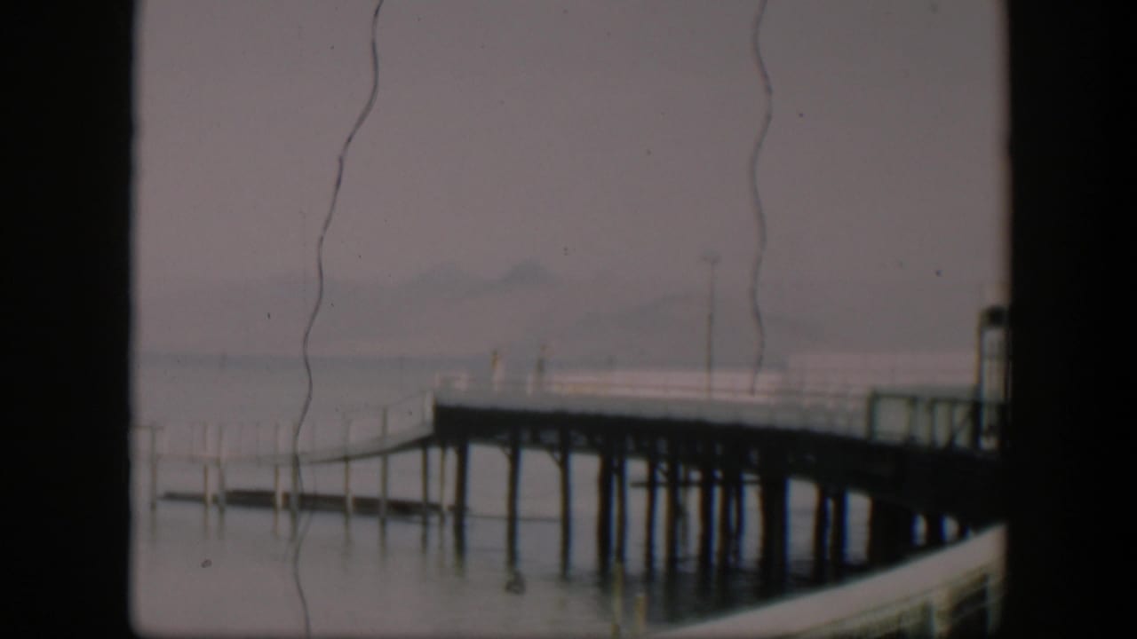 Pier and railings seen through haze, with vertical scratches across the frame.