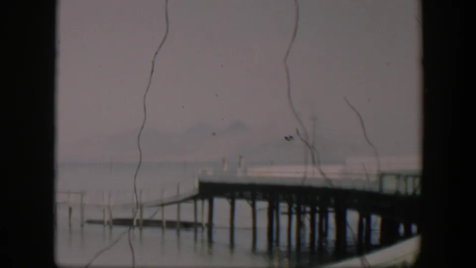 Soft 1951 Utah home-movie frame of a waterside pier, still water, and faint hills through fog.